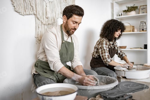 Preview: Man and woman potters crafting clay vases on potter's wheels