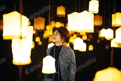Preview: Closeup shot of a happy young lady in a room with many bright chandeliers
