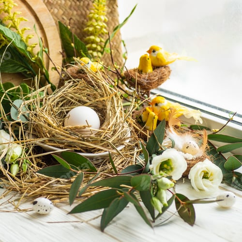 Preview: Easter egg in a nest with floral decoration near the window.