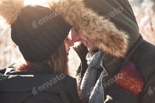Preview: Happy couple playful together during winter holidays vacation outside in snow park
