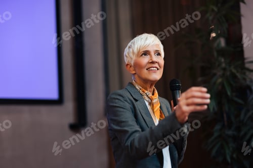 Preview: A smiling woman talking with a person from the audience, standing in the conference hall.