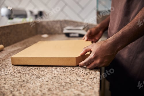 Preview: Male hands holding closed cardboard pizza box