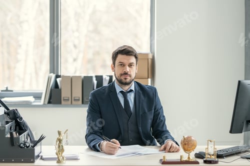 Preview: Bearded manager in suit sitting at desk