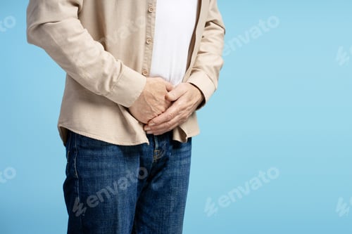 Preview: Senior man experiencing abdominal discomfort on blue background