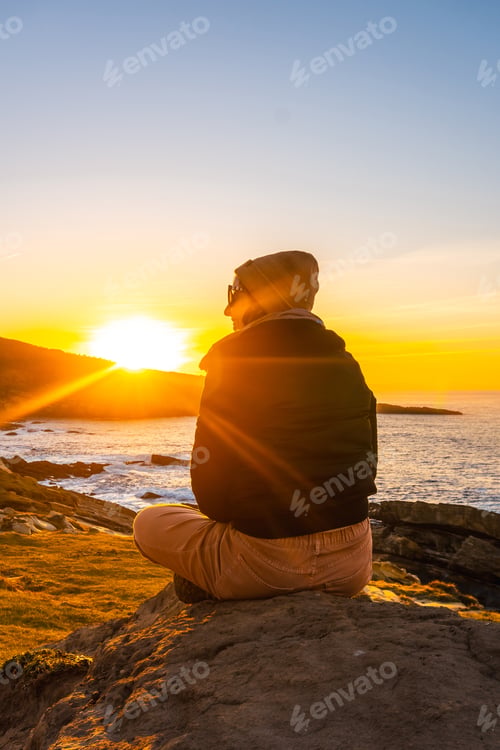 Preview: A relaxed young woman watching the sunset in the cove of stones