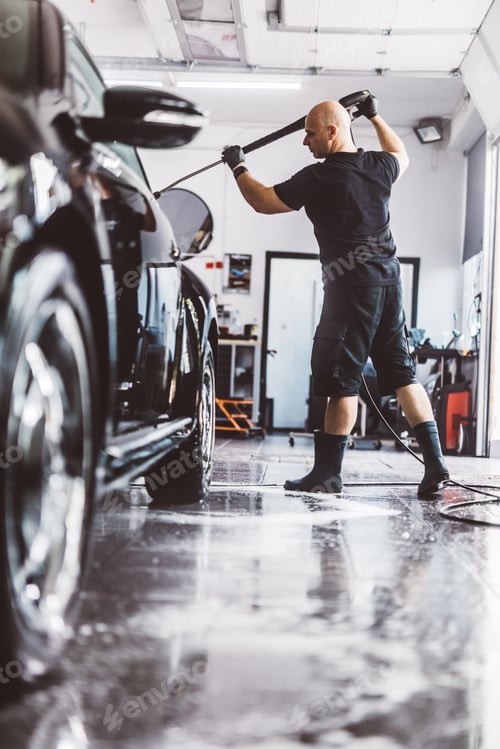 Preview: Service man washing car before detailing in workshop.