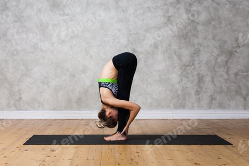 Preview: Attractive flexible girl standing forward bend in Uttanasana yoga pose