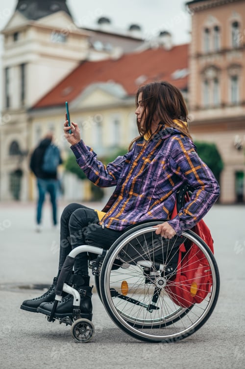 Preview: Woman in wheelchair taking a selfie with her smartphone while out in the city