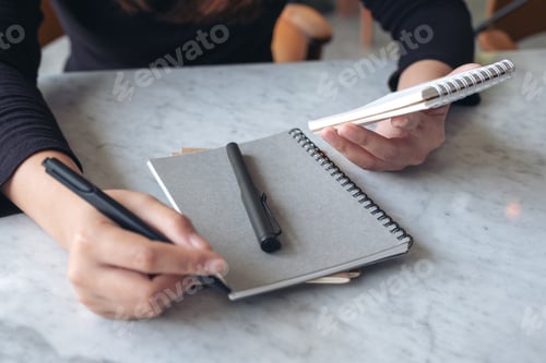 Preview: A woman holding and writing on notebook on the table