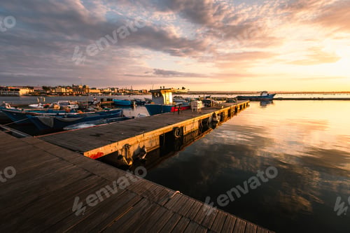 Preview: Taranto Vecchia pier at dawn with orange sky with clouds and moored boats
