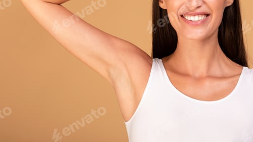 Preview: Positive young woman raising hand up and smiling, showing her clean and hairless armpit over beige
