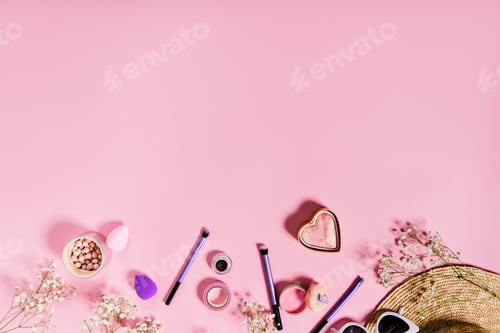 Preview: Blush, lilac makeup brushes and straw hat are located on isolated pink background.
