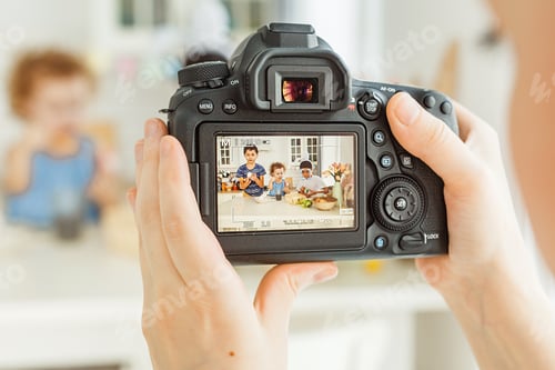 Preview: Woman’s hand holding the camera shooting while three children painting Easter eggs
