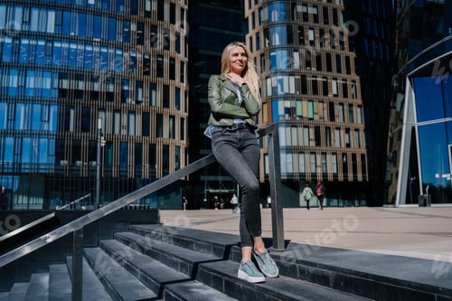 Preview: Beautiful hipster female standing on chairs outside against business center waiting for interview.