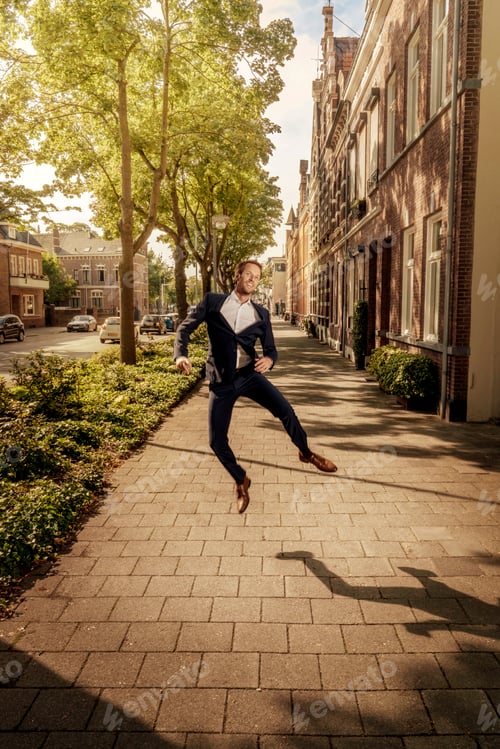Preview: Netherlands, Venlo, happy businessman jumping on pavement