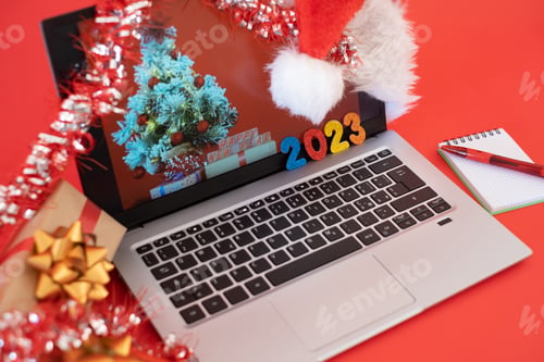 Preview: Desk with laptop at Christmas time, message of happy new year 2023 - red background