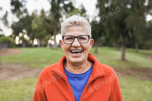 Preview: Senior caucasian woman smiling on camera outdoor at city park