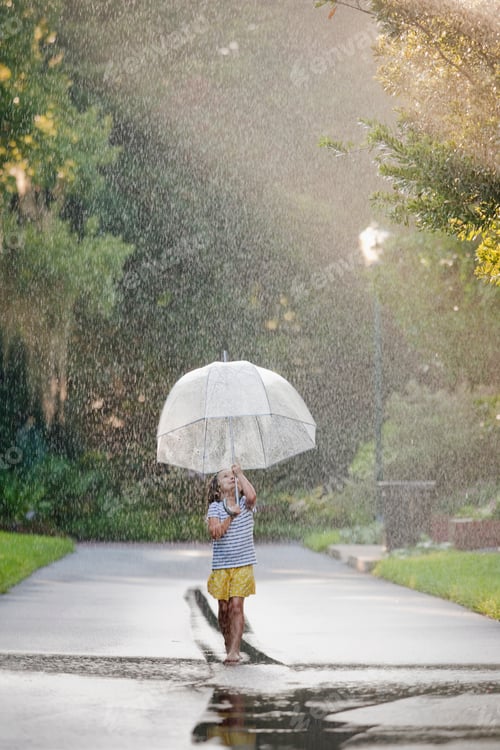 Preview: Barefoot girl holding up umbrella and walking through puddles on street