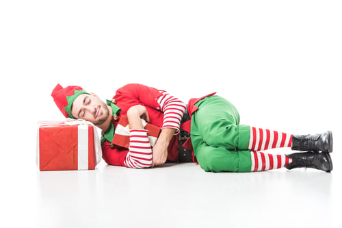 Preview: man in christmas elf costume sleeping on pile of presents isolated on white