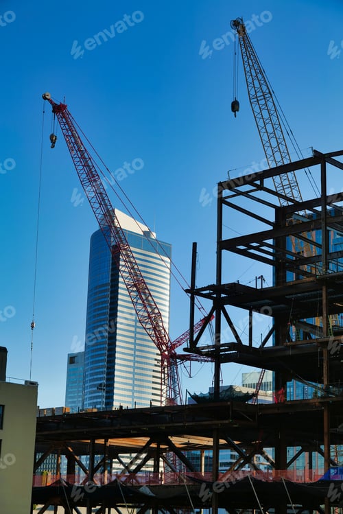 Preview: Cranes working on the construction area with high buildings in the background under a blue sky