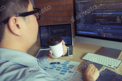 Preview: work with a program developer holding a coffee at the office and looking at the computer screen