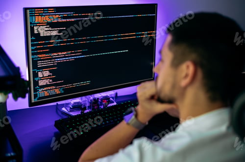 Preview: Successful male programmer sits in front of computer screen with programming code abstract