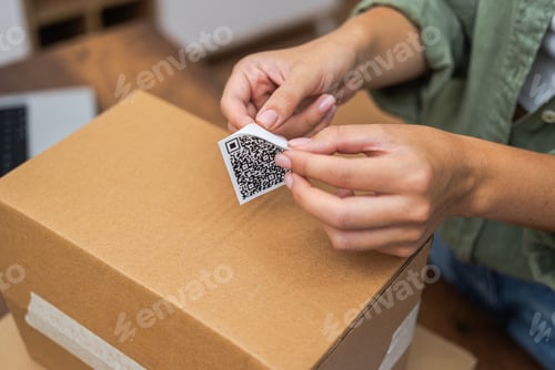 Preview: woman hands affix QR code sticker to package, e-commerce delivery and online shopping