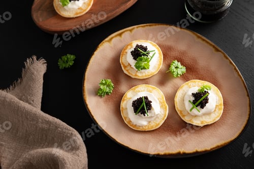 Preview: Black sturgeon caviar served on mini pancakes, appetizer from from fish products.