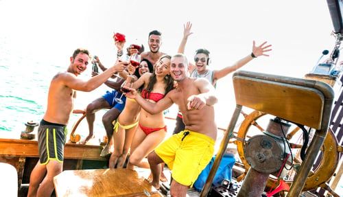 Preview: Multiracial millenial friends group having fun cheering at sail boat party