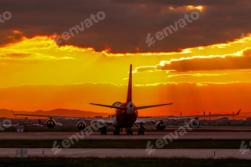 Preview: Aeroplane on a tarmac runway in a bright orange sunset background