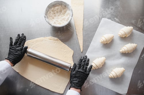 Preview: Baker rolling dough and preparing croissants in bakery