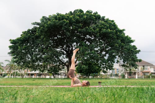 Preview: Woman in sporty outfit relaxing meditating feeling zen-like on fitness mat in public park outdoors