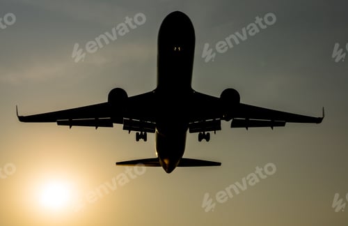 Preview: Low-angle shot of a silhouette of an aircraft about to land at sunset