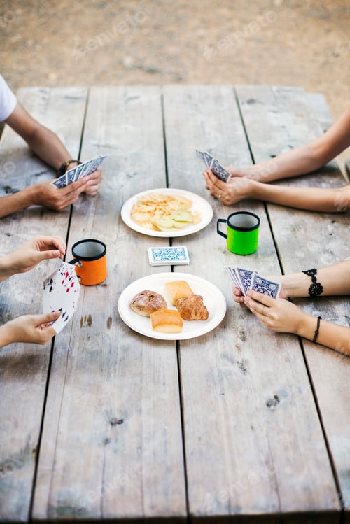 Preview: Close up of four people sitting at a table, playing cards.