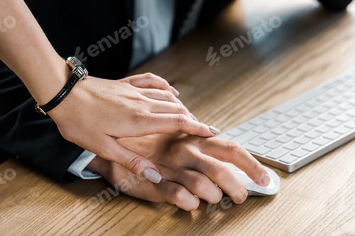 Preview: cropped shot of businesswoman holding colleagues hand while flirting
