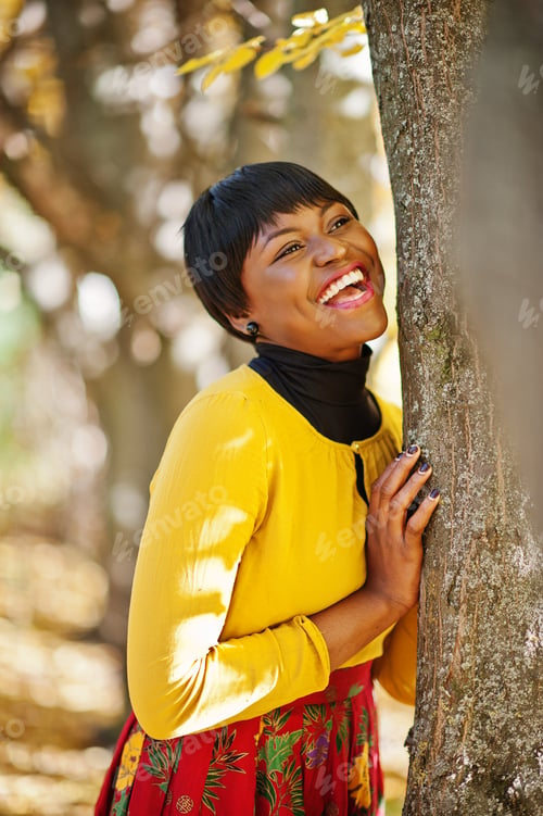 Aperçu: African american girl at yellow and red dress at golden autumn fall park.