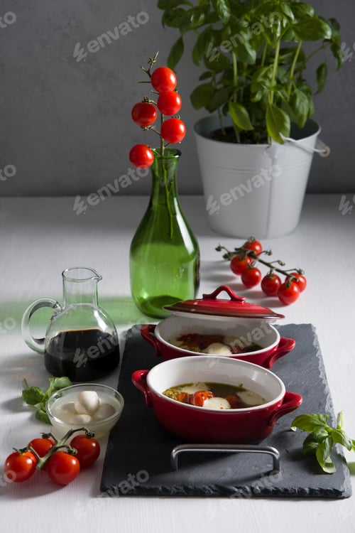 Preview: Italian caprese salad, baked cherry tomatoes, mozzarella and basil on a white table, still life