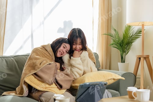 Preview: Winter day at home, women friends enjoy cozy friendship, sharing warm blankets, watching digital