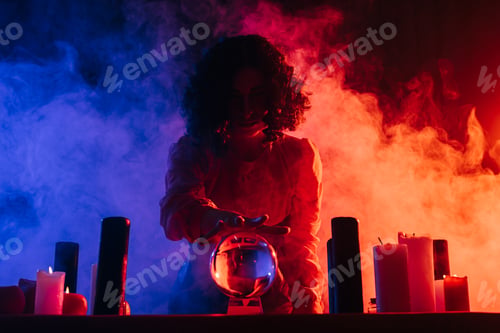 Preview: young fortune teller near crystal ball on dark background with colorful smoke