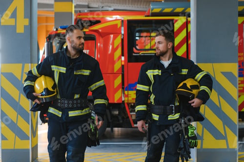 Preview: Two firefighters in protective clothing in helmets with fire engine