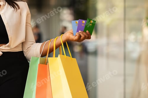 Preview: Unrecognizable black woman holding three credit cards and shopping bags