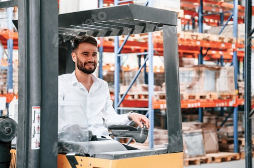 Preview: Using cargo moving machine. Storage worker is in the warehouse with bunch of products
