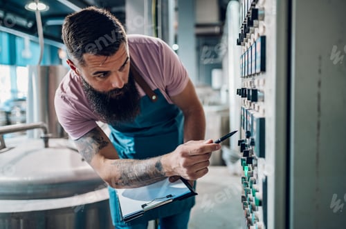 Preview: Man working in brewery and taking notes of the beer production