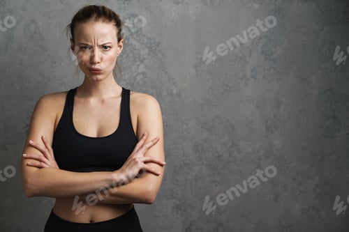 Preview: Young displeased woman in sports wear standing