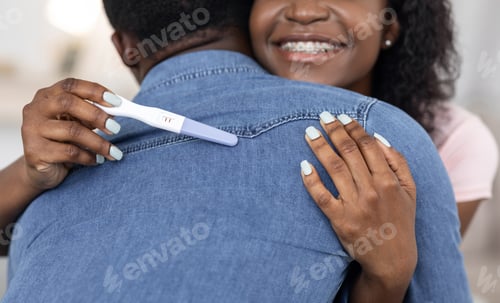 Preview: Cropped of african woman with pregnancy test hugging husband