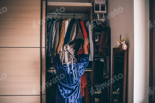 Preview: Woman with Braids Organizing Clothing in Closet