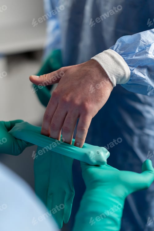 Preview: close-up of a doctor's hands a surgeon puts on green latex gloves before an operation