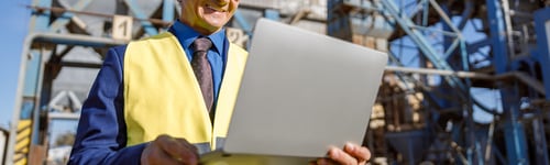 Preview: Cheerful male engineer using laptop outdoors at factory