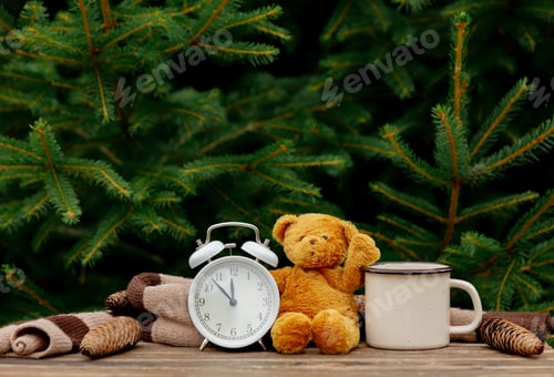 Preview: vintage alarm clock, teddy bear and cup of coffee on wooden table with spruce branches on background