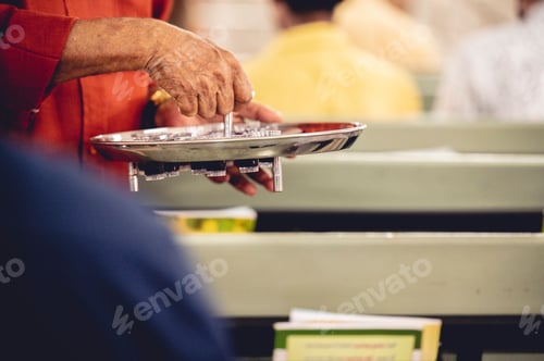 Preview: Person treats the red wine with small glasses to churchgoers to observe communion